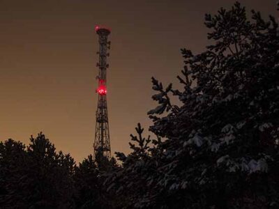 Communications structure with red tower light at night